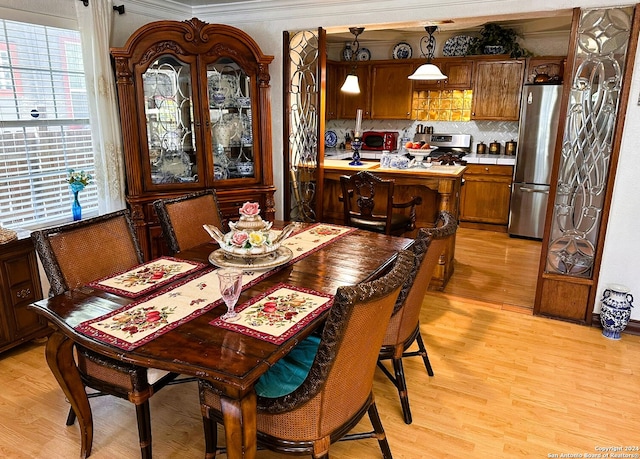 dining space featuring ornamental molding and light hardwood / wood-style flooring