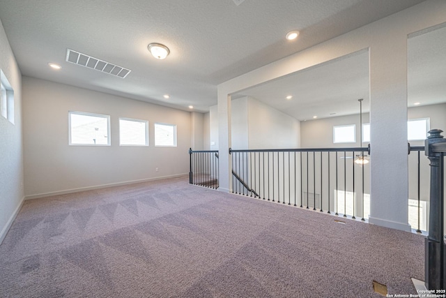 spare room featuring visible vents, a wealth of natural light, carpet, and baseboards