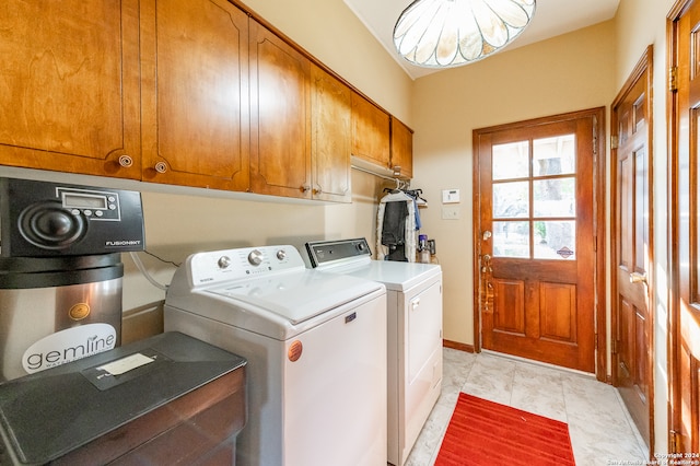 clothes washing area with light tile patterned flooring, cabinets, and washing machine and clothes dryer