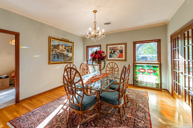 dining area with light hardwood / wood-style flooring, ornamental molding, and a notable chandelier