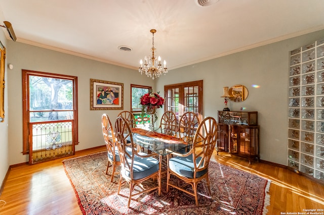 dining space with a chandelier, crown molding, and light hardwood / wood-style floors