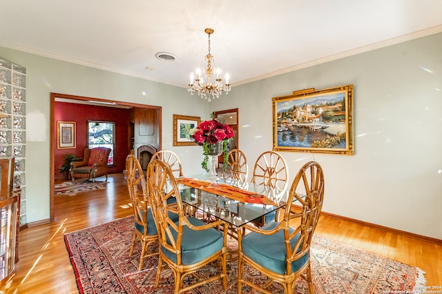 dining area with crown molding, a notable chandelier, and light wood-type flooring