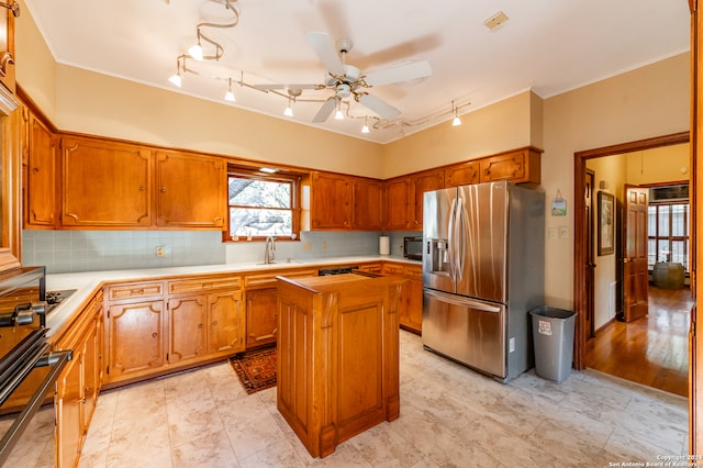 kitchen with stainless steel fridge, tasteful backsplash, ceiling fan, sink, and a center island