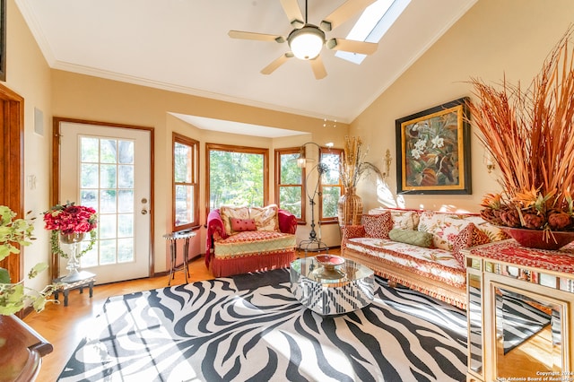 living room featuring vaulted ceiling with skylight, crown molding, light wood-type flooring, and ceiling fan