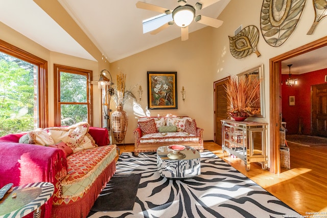 living room featuring hardwood / wood-style floors, high vaulted ceiling, ornamental molding, ceiling fan with notable chandelier, and a skylight