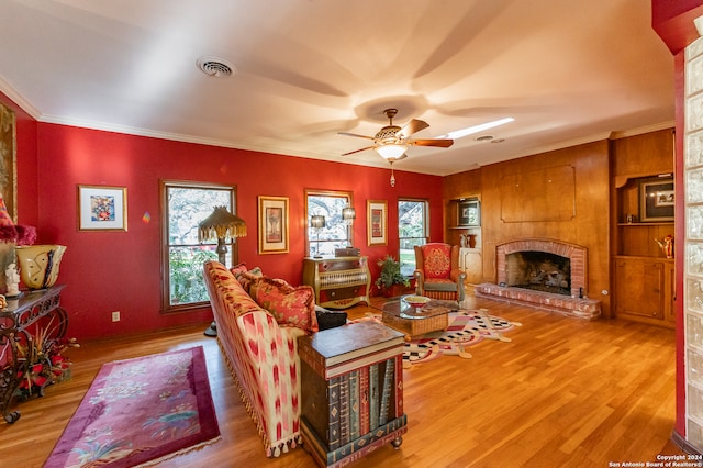 living room featuring light hardwood / wood-style floors, ornamental molding, a brick fireplace, and plenty of natural light