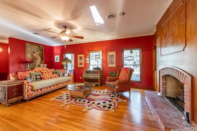 living area with ornamental molding, wood-type flooring, a fireplace, and ceiling fan