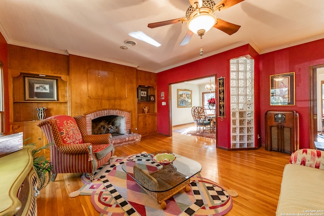 living room with crown molding, hardwood / wood-style flooring, a fireplace, and ceiling fan