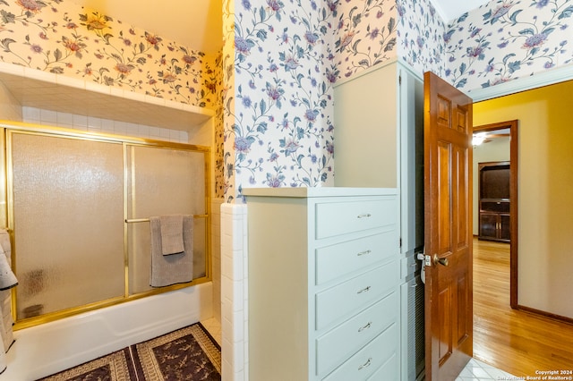 bathroom with combined bath / shower with glass door and wood-type flooring