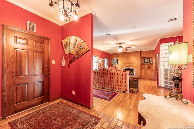 entrance foyer with ornamental molding, hardwood / wood-style floors, a fireplace, and ceiling fan