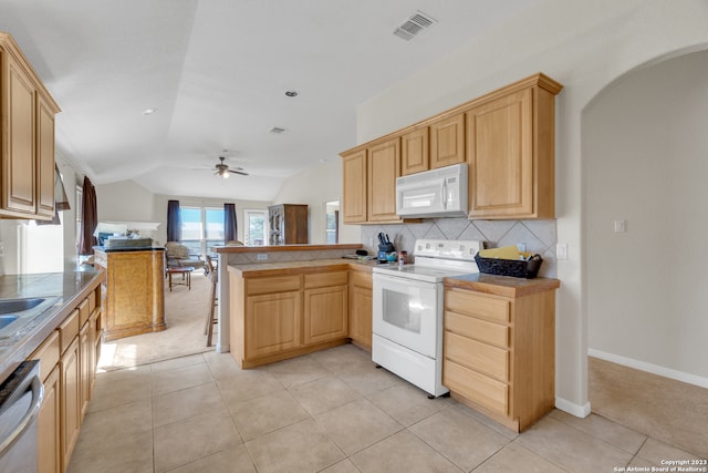 kitchen with lofted ceiling, kitchen peninsula, light tile patterned floors, white appliances, and ceiling fan