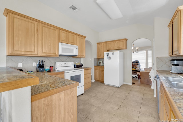 kitchen with a notable chandelier, light brown cabinetry, backsplash, and white appliances