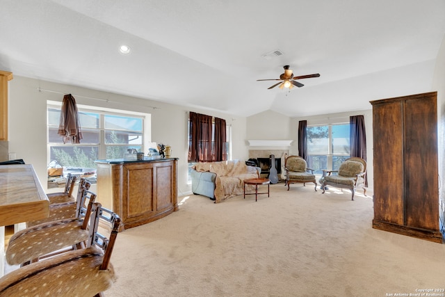 living room with vaulted ceiling, a healthy amount of sunlight, a fireplace, and ceiling fan