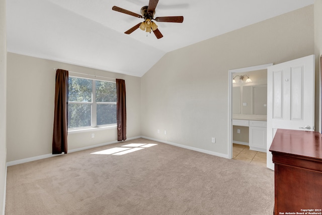 unfurnished bedroom with light colored carpet, connected bathroom, vaulted ceiling, and ceiling fan