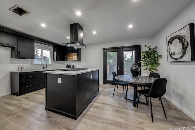 kitchen with french doors, stainless steel gas cooktop, a center island, light hardwood / wood-style flooring, and island exhaust hood