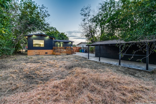 yard at dusk featuring a wooden deck and a patio