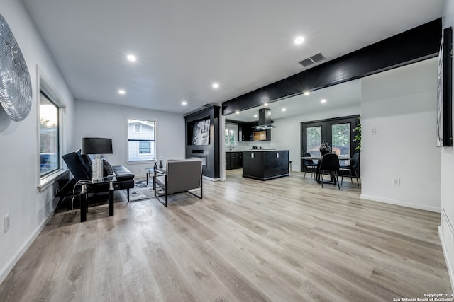 living room with plenty of natural light, light wood-type flooring, and french doors