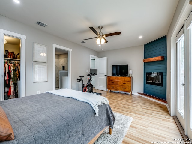 bedroom featuring a spacious closet, multiple windows, light wood-type flooring, and ceiling fan