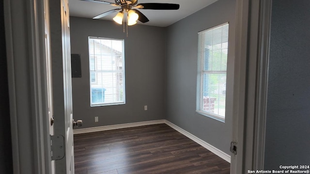 empty room with dark hardwood / wood-style floors, a healthy amount of sunlight, and ceiling fan