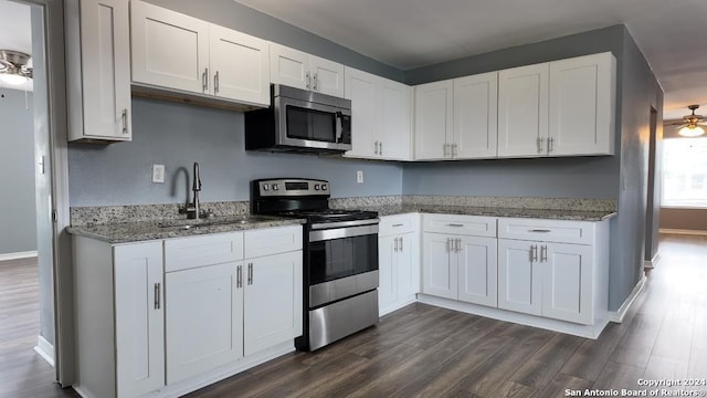 kitchen featuring dark wood-type flooring, appliances with stainless steel finishes, white cabinetry, and ceiling fan