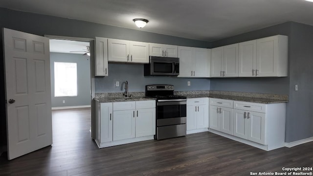 kitchen featuring dark wood-type flooring, appliances with stainless steel finishes, white cabinets, and ceiling fan