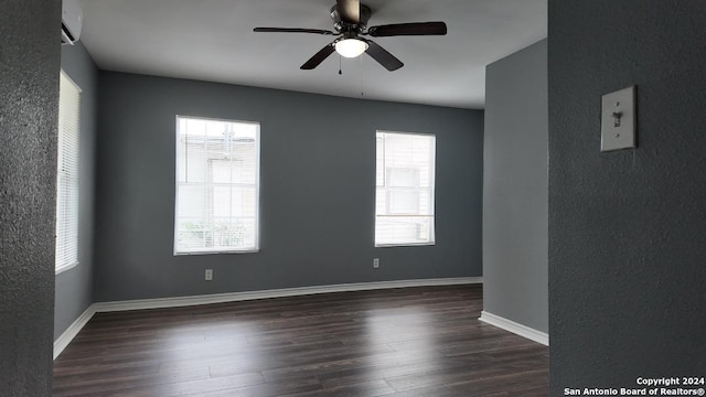 empty room featuring a wall mounted air conditioner, dark hardwood / wood-style floors, and ceiling fan