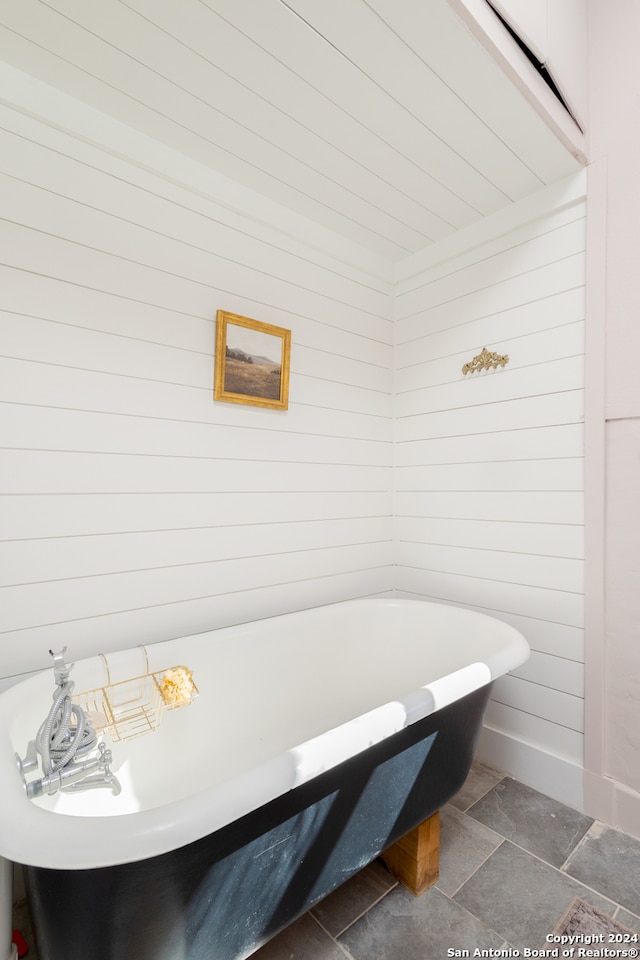 bathroom with a tub to relax in and wooden walls