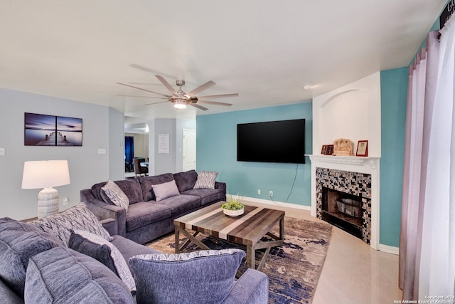 living room with a tiled fireplace and ceiling fan