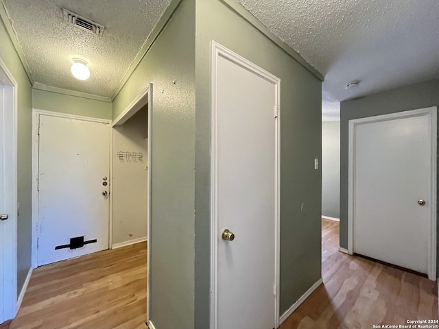 corridor featuring light hardwood / wood-style flooring and a textured ceiling