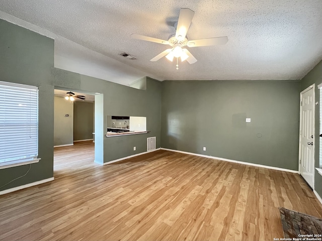 unfurnished living room featuring lofted ceiling, a textured ceiling, and light hardwood / wood-style floors