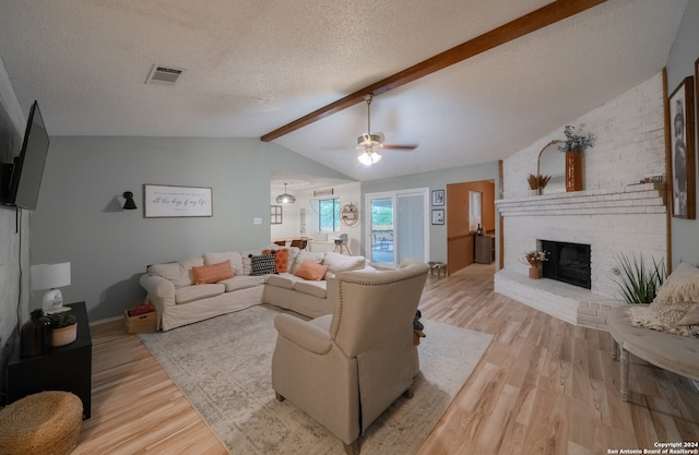 living room with light hardwood / wood-style floors, ceiling fan, vaulted ceiling with beams, and a brick fireplace