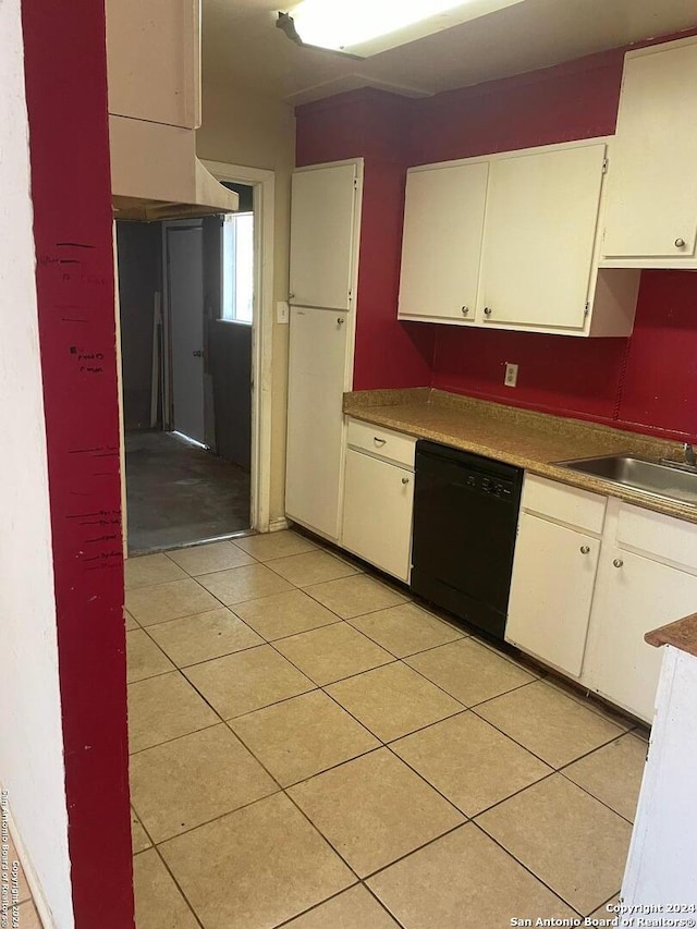 kitchen featuring sink, black dishwasher, light tile patterned floors, and white cabinets