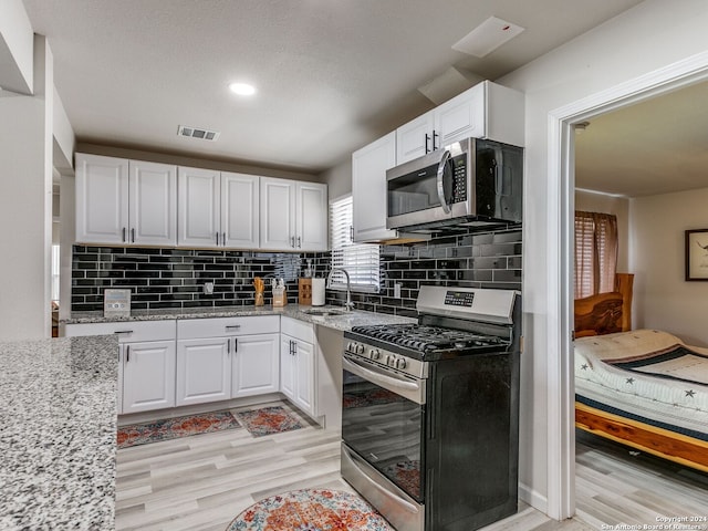 kitchen with white cabinetry, stainless steel appliances, and light wood-type flooring