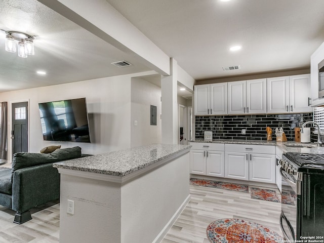 kitchen featuring decorative backsplash, sink, a center island, light wood-type flooring, and white cabinetry