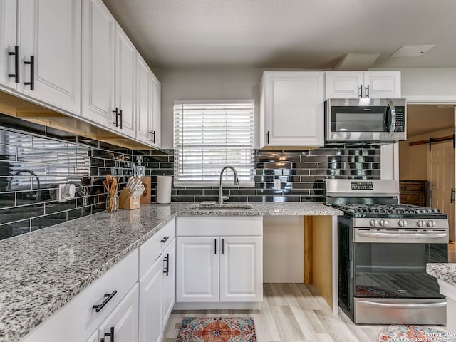 kitchen featuring light hardwood / wood-style floors, appliances with stainless steel finishes, sink, and white cabinets