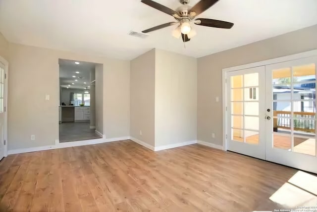 spare room featuring ceiling fan, a healthy amount of sunlight, light wood-type flooring, and french doors