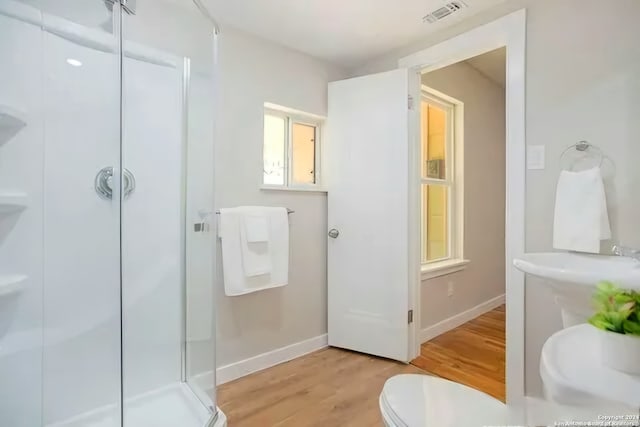 bathroom with toilet, wood-type flooring, and walk in shower