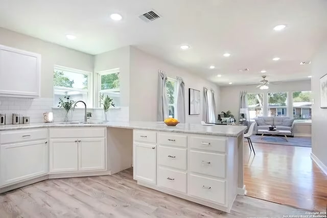 kitchen featuring white cabinets, sink, decorative backsplash, ceiling fan, and light wood-type flooring