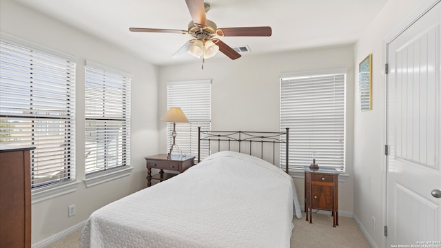 bedroom featuring multiple windows, light colored carpet, and ceiling fan