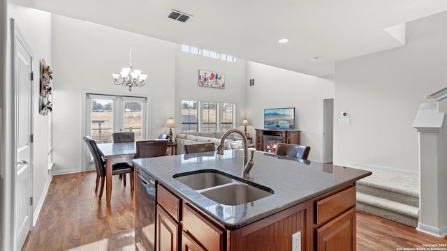 kitchen with hardwood / wood-style floors, hanging light fixtures, a center island with sink, dishwasher, and sink