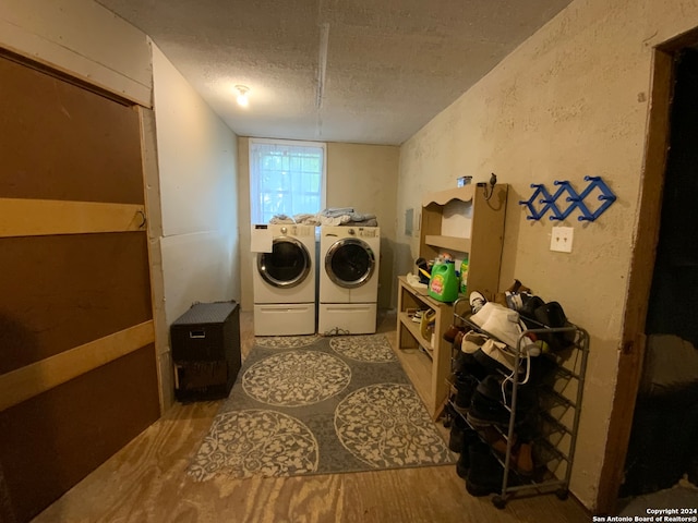 clothes washing area featuring washing machine and dryer, a textured ceiling, and hardwood / wood-style floors