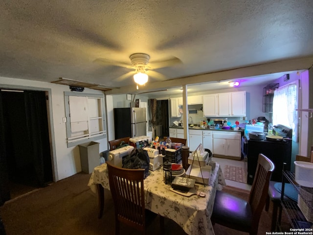 dining area with sink, carpet flooring, a textured ceiling, and ceiling fan