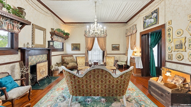 sitting room with an inviting chandelier, ornamental molding, hardwood / wood-style flooring, and a tile fireplace