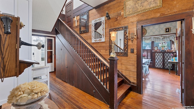 staircase featuring wooden walls, wood-type flooring, and a towering ceiling