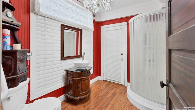 bathroom featuring hardwood / wood-style flooring, toilet, ornamental molding, a shower with shower door, and vanity