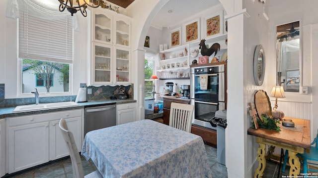 kitchen featuring appliances with stainless steel finishes, decorative backsplash, white cabinetry, and sink