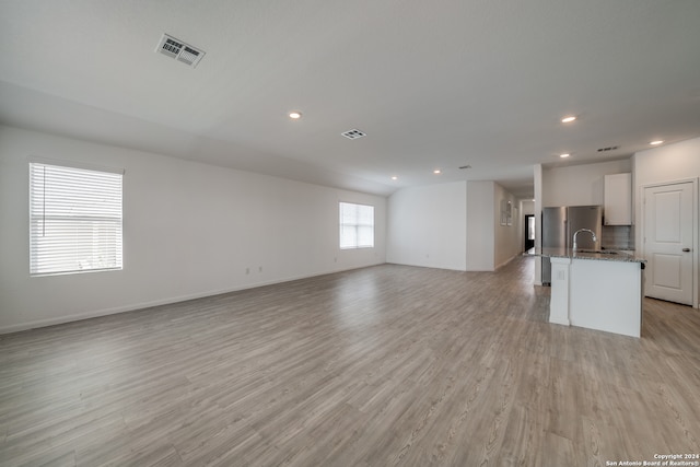 unfurnished living room featuring light hardwood / wood-style floors and sink