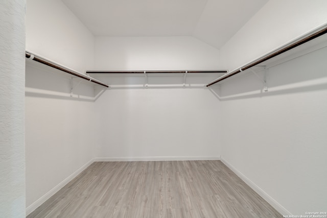 walk in closet with light hardwood / wood-style flooring and vaulted ceiling