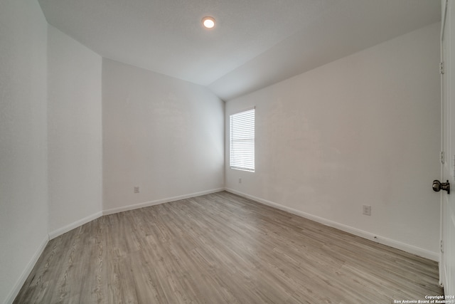 empty room featuring light hardwood / wood-style flooring and vaulted ceiling