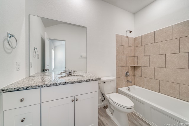 full bathroom with vanity, hardwood / wood-style floors, tiled shower / bath combo, and toilet